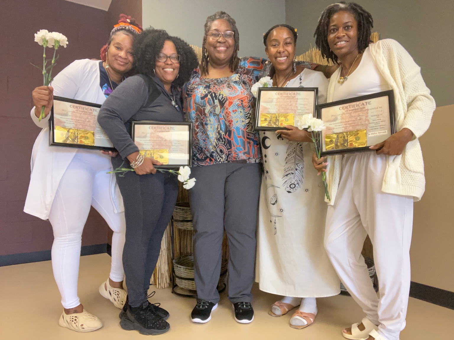 Janine and four practitioners smiling with completion certificates and flowers